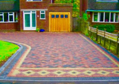 Block paving driveway with patterns leading to garage