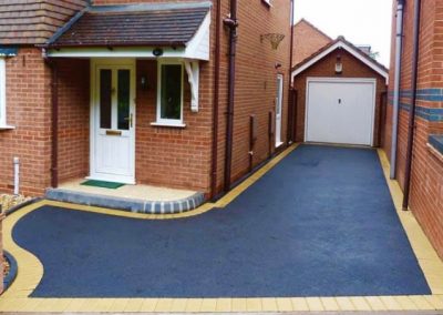 Dark tarmac driveway with a light brick border